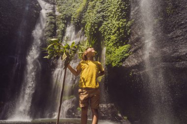 Tatlı çocuk ormanın kralını bir şelalenin arka planında tasvir ediyor. Aletsiz çocukluk kavramı. Çocuk konseptiyle seyahat etmek. Çocukluk kavramı.