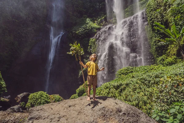 Der süße Junge zeigt den König des Dschungels vor dem Hintergrund eines Wasserfalls. Kindheit ohne Schnickschnack. Reisen mit Kindern. Konzept "Kindheit im Freien" — Stockfoto