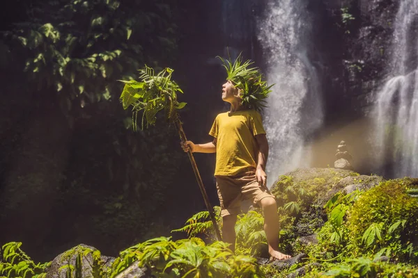 Симпатичный мальчик изображает короля джунглей на фоне водопада. Детство без концепции гаджетов. Путешествие с детской концепцией. Детство на открытом воздухе — стоковое фото
