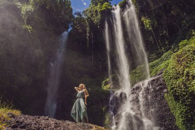 Endonezya 'nın Bali adasındaki Sekumpul şelalelerinde turkuaz elbiseli bir kadın. Bali Seyahat Konsepti