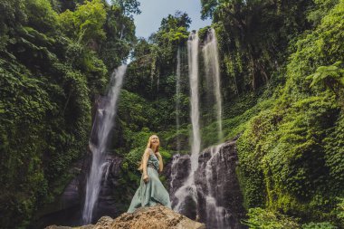 Endonezya 'nın Bali adasındaki Sekumpul şelalelerinde turkuaz elbiseli bir kadın. Bali Seyahat Konsepti