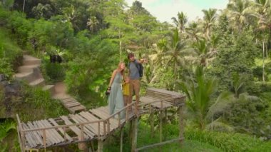 Bali adasındaki Ubud köyündeki ünlü Tegalalang Rice Teraslarını ziyaret eden mutlu bir aile turistinin hava görüntüsü.