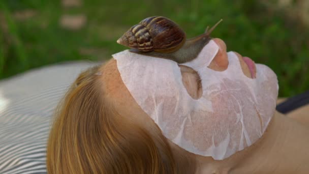 年轻女人用蜗牛状的黏液做了一个面罩. 戴着面具爬行的蜗牛 — 图库视频影像