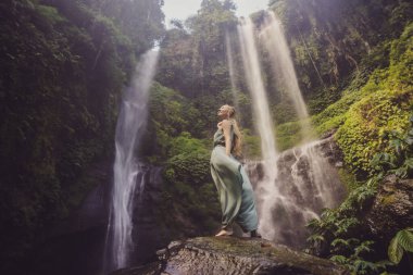 Endonezya 'nın Bali adasındaki Sekumpul şelalelerinde turkuaz elbiseli bir kadın. Bali Seyahat Konsepti