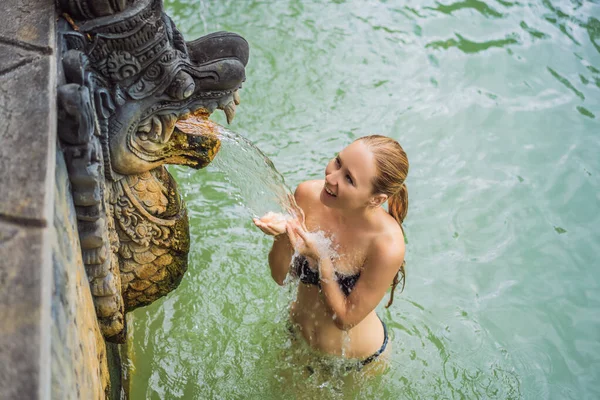 Jonge vrouw in warmwaterbron banjar. Thermaal water komt vrij uit de mond van beelden bij een warmwaterbron in Banjar, Bali, Indonesië — Stockfoto