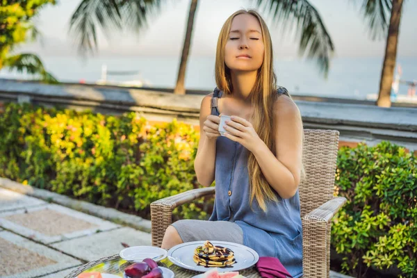 Молодая женщина с романтическим завтраком на рассвете в курортном ресторане на открытом воздухе. Здоровый напиток на завтрак. Красивая женщина в отпуске — стоковое фото