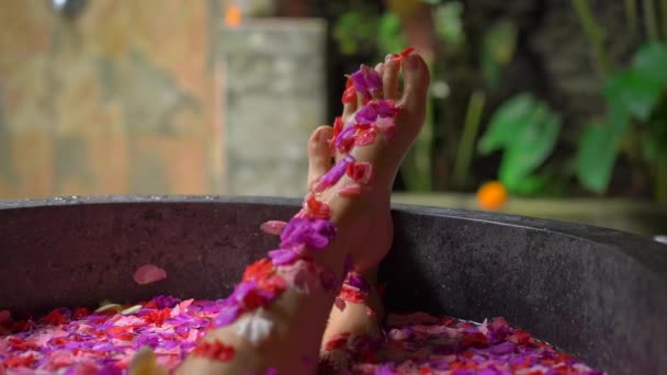 Fotografía en cámara lenta de una hermosa joven tomando un baño floral en un spa tropical — Vídeos de Stock