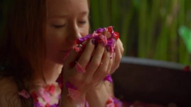 Genç ve güzel bir kadının tropikal bir kaplıcada çiçek banyosu yaparken yavaş çekim.