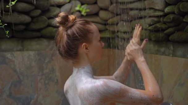 Slowmotion shot of a young woman in a tropical spa. She takes a shower after taking a moisturizer compound — Stock Video