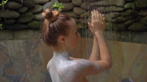 Zpomalený záběr mladé ženy v tropických lázních. Sprchuje se po tom, co si vzala hydratační směs. — Stock video