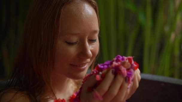 Genç ve güzel bir kadının tropikal bir kaplıcada çiçek banyosu yaparken yavaş çekim. — Stok video