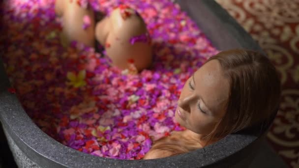 Lambat ditembak seorang wanita muda yang cantik mengambil mandi bunga di spa tropis — Stok Video