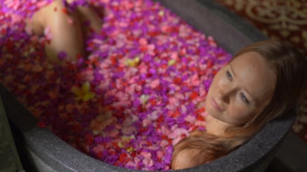 Fotografía en cámara lenta de una hermosa joven tomando un baño floral en un spa tropical — Vídeo de stock