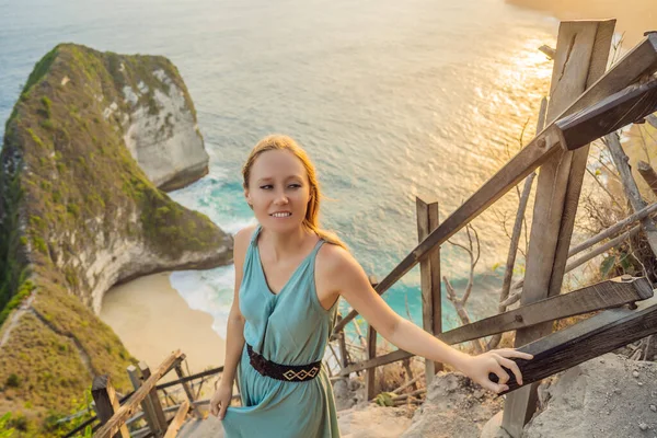 Family vacation lifestyle. Happy woman stand at viewpoint. Look at beautiful beach under high cliff. Travel destination in Bali. Popular place to visit on Nusa Penida island — Stock Photo, Image