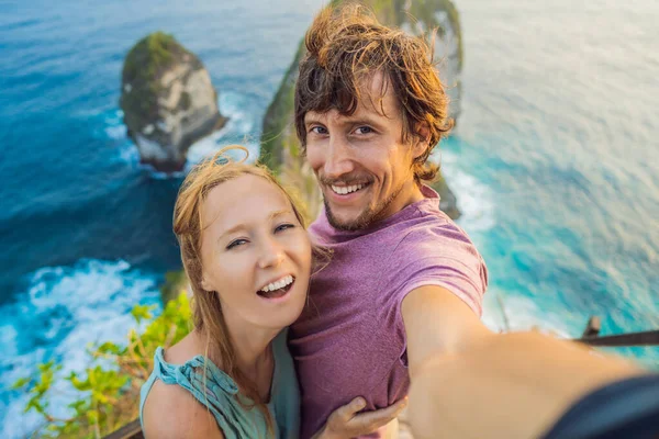 Семейный отдых. Счастливая пара - мужчина и женщина стоят на точке зрения. Посмотрите на красивый пляж под высоким обрывом. Путешествие на Бали. Популярное место для посещения на острове Нуса Пенида — стоковое фото