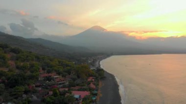 Amed bölgesindeki güzel Jemeluk Koyu 'nun muhteşem Agung volkanı manzaralı havadan çekimi. Amed 'de günbatımı. Bali konseptine Seyahat