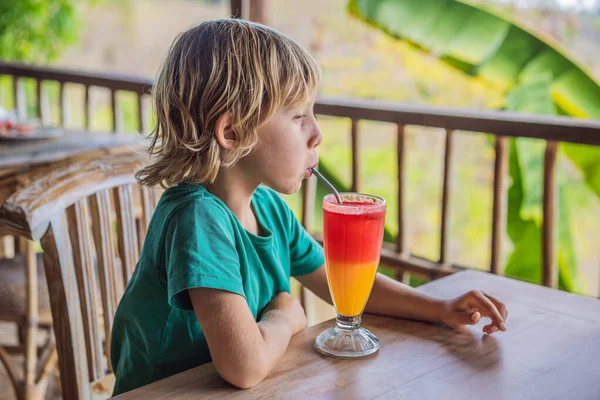 Pojke dricker två ton cocktail i ett glas i caféet — Stockfoto