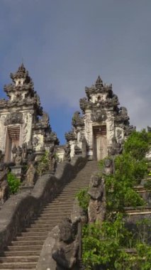 Dikey video. Endonezya 'daki Bali Adası' ndaki Pura Lempuyang Tapınağı 'nda merdivenleri koruyan taş ejderhaların el kamerası görüntüsü.