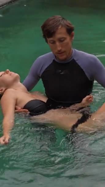Vídeo vertical. Hombre realizando masaje watsu estilo japonés para una mujer en una piscina — Vídeos de Stock
