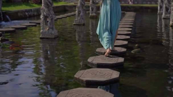 Spowolnione ujęcie młodej kobiety odwiedzającej wodny pałac Tirta Gangga, dawny pałac królewski na wyspie Bali, Indonezja — Wideo stockowe