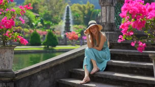 Una joven turista visitando el palacio de agua Tirta Gangga, antiguo palacio real en la isla de Bali, Indonesia — Vídeo de stock
