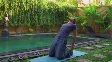 Genç adam yüzme havuzunda yoga yapıyor.