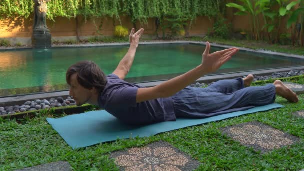 Joven practica yoga junto a una piscina — Vídeo de stock