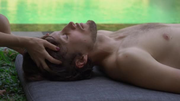 Bir kadın terapistin, genç bir adama özel villasında havuz kenarında masaj yaparken yakın plan fotoğrafı. ev masaj servisi — Stok video