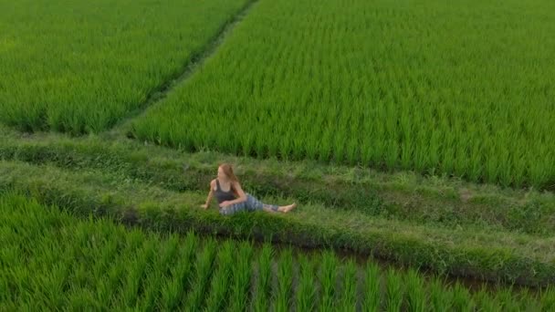 日出日落时，一个女人在一片神奇的稻田里练瑜伽的空中镜头 — 图库视频影像