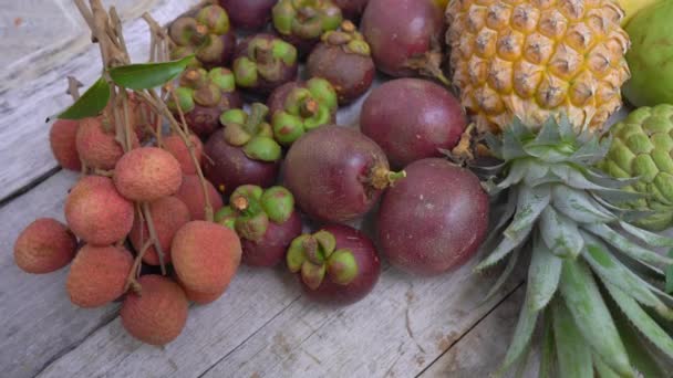 Muitas frutas tropicais em um fundo de madeira — Vídeo de Stock