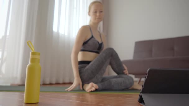 Mulher fitness se exercitando no chão em casa e assistindo vídeos de fitness em um tablet. As pessoas praticam esportes online por causa do coronovírus — Vídeo de Stock