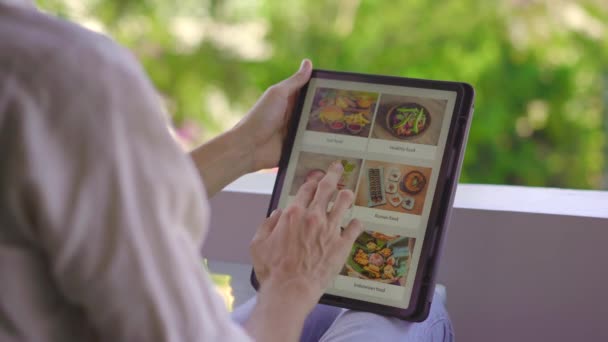 Un hombre pide comida para el almuerzo en línea usando la tableta. Concepto de compras en línea — Vídeos de Stock