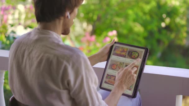 Un hombre pide comida para el almuerzo en línea usando la tableta. Concepto de compras en línea — Vídeos de Stock