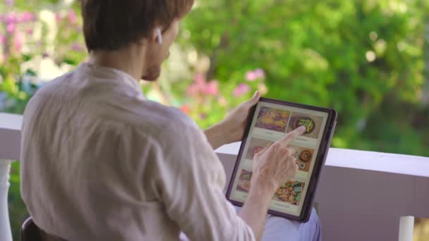 Ένας άντρας παραγγέλνει φαγητό στο διαδίκτυο χρησιμοποιώντας τάμπλετ. Έννοια online shoping — Αρχείο Βίντεο