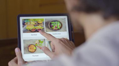 Bir adam tabletle internetten yemek sipariş ediyor. Çevrimiçi alışveriş kavramı
