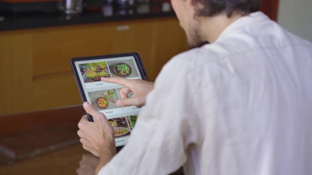 Мужчина заказывает еду на обед онлайн с помощью планшета. Концепция интернет-магазинов — стоковое видео
