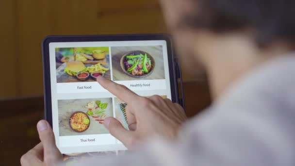 Un hombre pide comida para el almuerzo en línea usando la tableta. Concepto de compras en línea — Vídeos de Stock