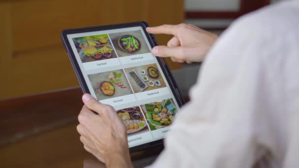 Um homem pede comida para o almoço on-line usando tablet. Conceito de compras online — Vídeo de Stock