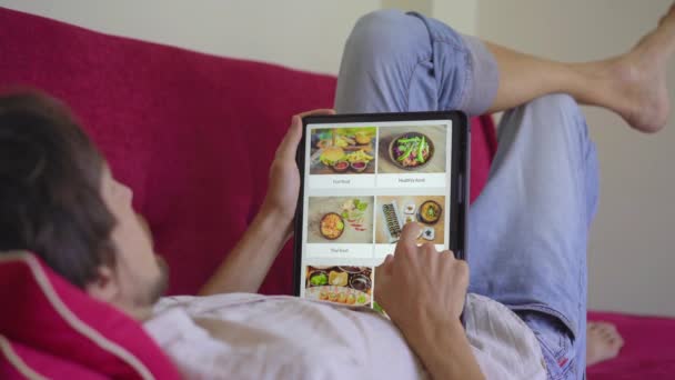 Mężczyzna zamawia jedzenie na lunch przez internet za pomocą tabletu. Koncepcja zakupów online — Wideo stockowe