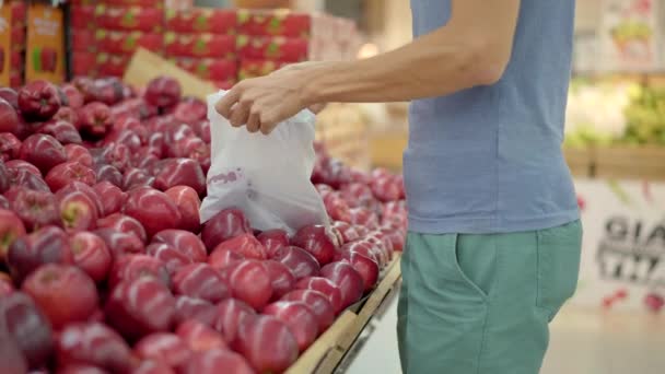 Zaniepokojony mężczyzna nosi maskę medyczną przeciwko koronawirusowi, kupując jedzenie w supermarkecie lub sklepie. Kwarantanna się skończyła, teraz możesz iść do sklepu odzieżowego, ale musisz założyć maskę. Zdrowie — Wideo stockowe