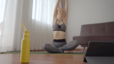 Spor salonundaki kadın evde egzersiz yapıyor ve tabletle spor salonu videoları izliyor. İnsanlar koronovirüs yüzünden spor yapıyor. Tablete odaklan.