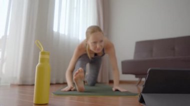Spor salonundaki kadın evde egzersiz yapıyor ve tabletle spor salonu videoları izliyor. İnsanlar koronovirüs yüzünden spor yapıyor. Tablete odaklan.