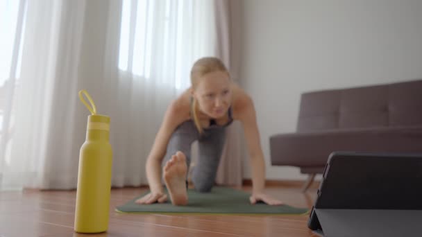Mujer fitness haciendo ejercicio en el suelo en casa y viendo videos de fitness en una tableta. La gente hace deportes en línea debido al coronovirus. Concéntrate en la tableta — Vídeos de Stock
