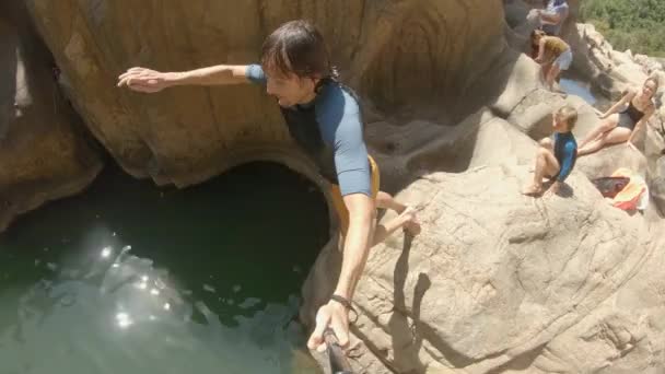 Photo ralentie d'un jeune homme s'enregistrant lui-même sautant d'une falaise dans une rivière. Concept d'été — Video