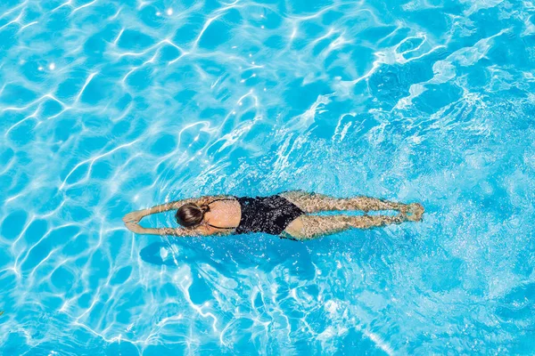 Γυναίκα με μαύρο μαγιό που κολυμπάει σε μια γαλάζια πισίνα — Φωτογραφία Αρχείου