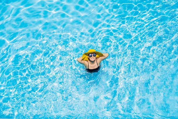 Mujer sentada en una piscina con un gran sombrero amarillo —  Fotos de Stock