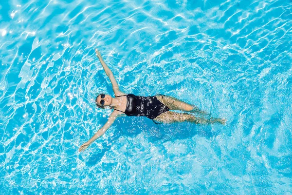 Mulher de óculos de sol nada na piscina — Fotografia de Stock