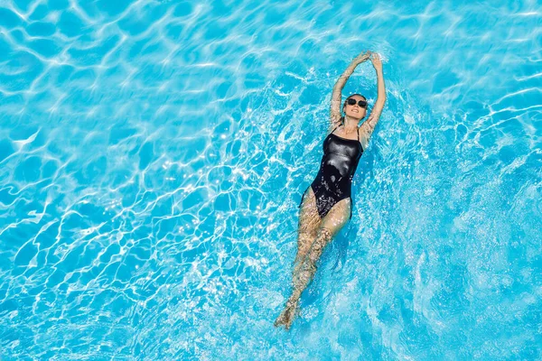 Femme en lunettes de soleil nage dans la piscine — Photo