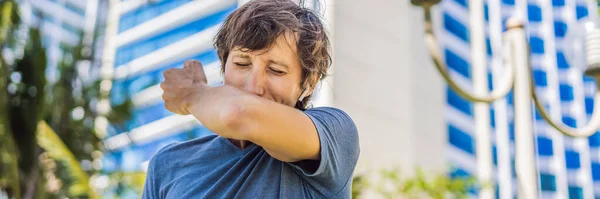 How to sneeze correctly. Man sneezes on the elbow. Concept of the spread of the virus BANNER, LONG FORMAT — Stock Photo, Image