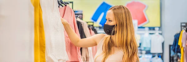 Woman in a clothing store in a medical mask because of a coronovirus. Quarantine is over, now you can go to the clothing store BANNER, LONG FORMAT